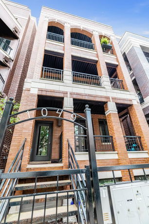 Front view of a multi-story building with a brick facade and balconies.