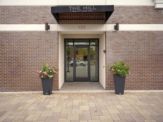 Front entrance of a building with brick facade and glass doors.