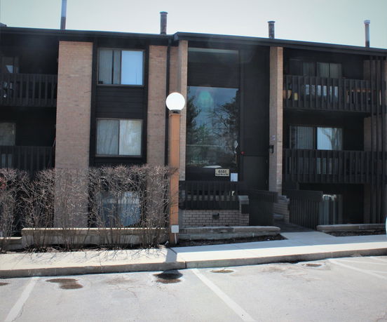 Front view of a multi-story brick residential building with balconies.