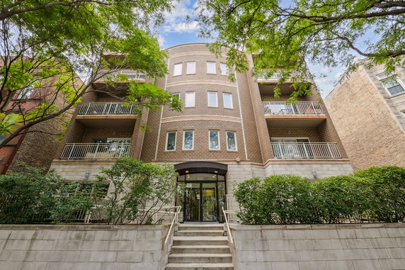 Front view of a multi-story brick apartment building with balconies.