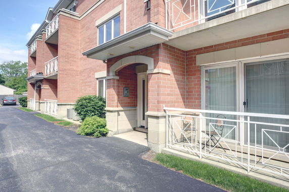 Front view of a brick residential building with balconies and a small patio area.
