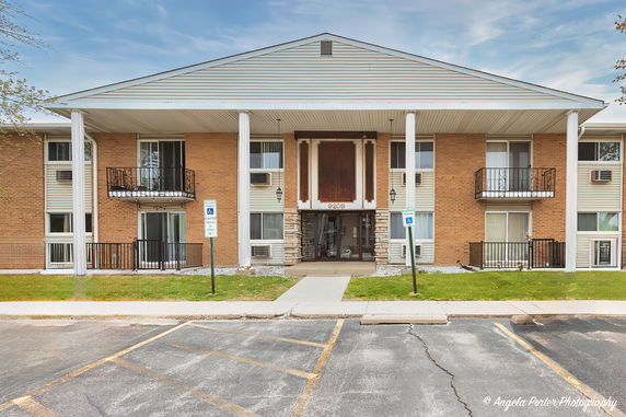 Front view of a multi-story residential building with balconies and a central entrance.