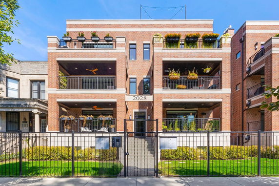 Front view of a multi-story brick apartment building with balconies.