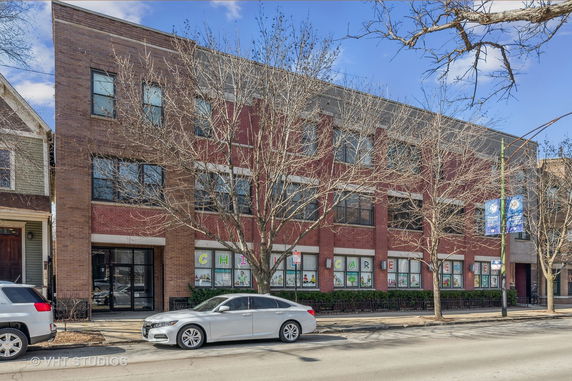 Front view of a three-story brick building with large windows.