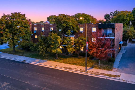 Front view of a multi-story brick building with trees in front.