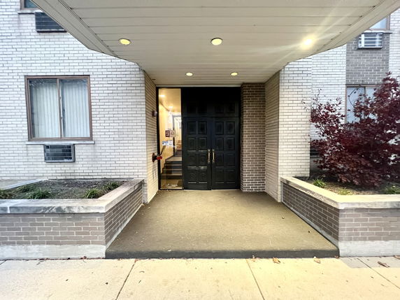 Front view of a building entrance with dark double doors and brick facade.