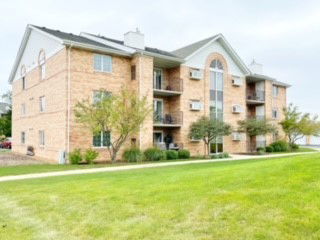 Front view of a multi-story apartment building with brick facade and balconies.