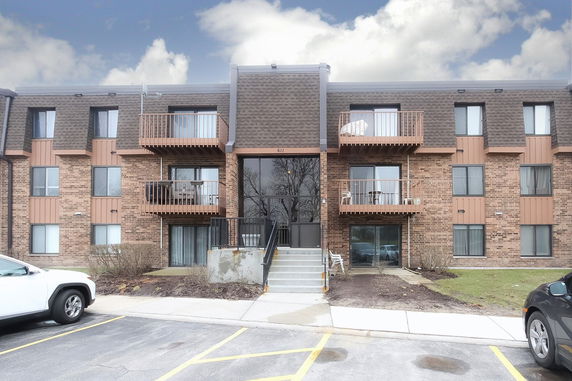 Front view of a multi-story brick apartment building with balconies.