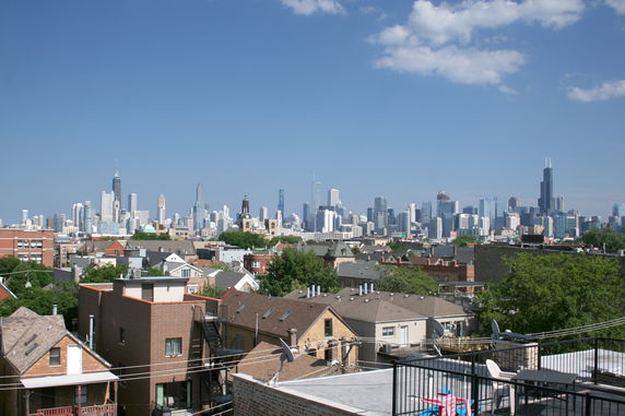 Panoramic view of a city skyline with a mix of skyscrapers and residential buildings under a blue sky.