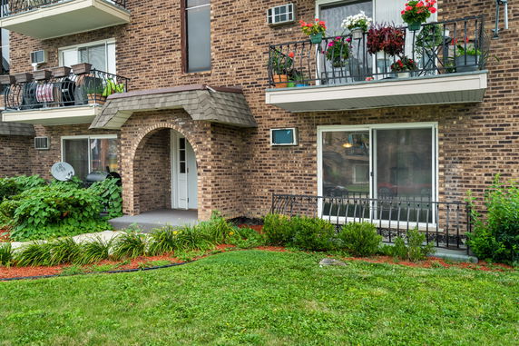 Front view of a brick building with balconies and an arched entrance.