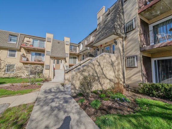 Front view of a multi-story residential building with balconies and sloped roof.