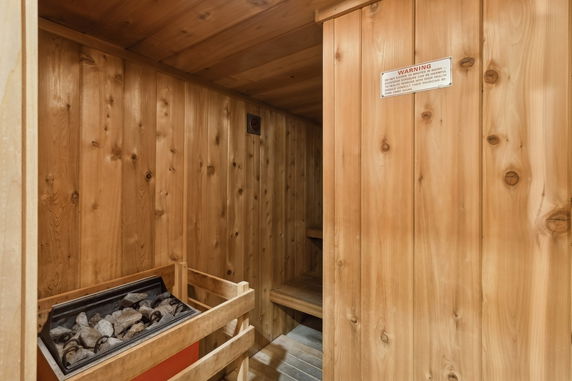 Wood-paneled sauna room with heated stones.