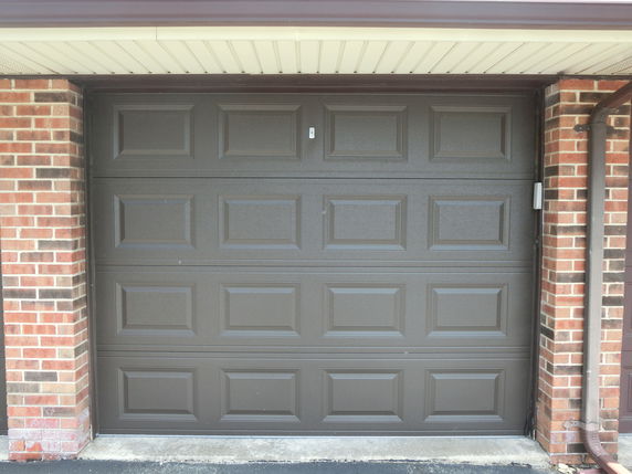 Front view of a garage door with brick siding.
