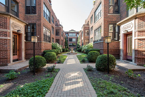 Front view of a brick apartment complex with pathways and landscaped gardens.