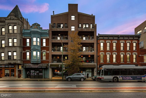 Front view of a multi-story building with a brick facade and balconies.