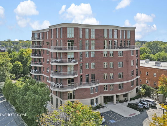 Front view of a multi-story brick apartment building with balconies.