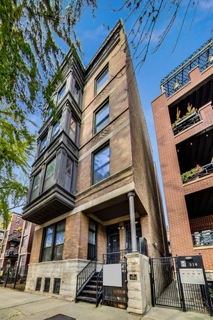 Front view of a multi-story brick residential building with decorative windows.