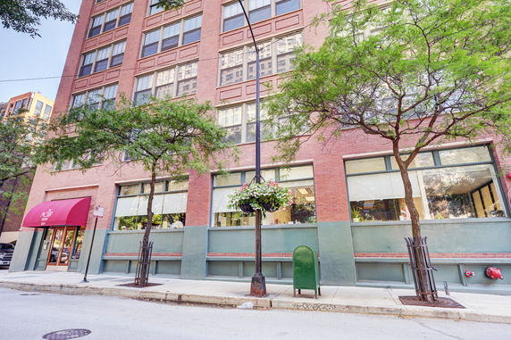 Front view of a multi-story brick building with large windows.