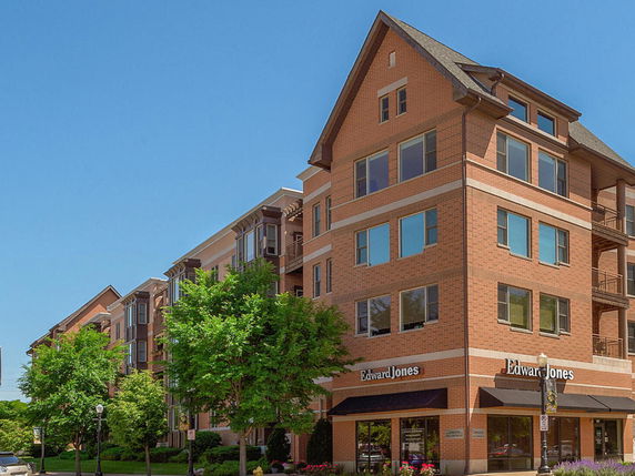 Front view of a multi-story brick building with a gabled roof and large windows.