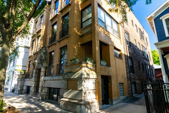 Front view of a multi-story brownstone building with ornate details and large windows.