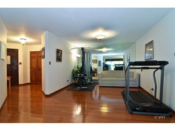 Indoor area with gym equipment including a treadmill and weight machine, and a couch.