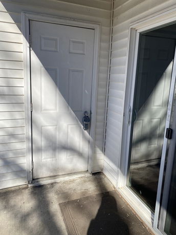 Front view of a house entrance with a white door and sliding glass door.