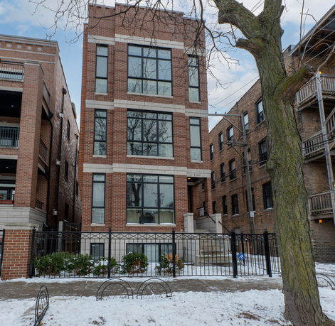 Front view of a multi-story brick building with large windows.