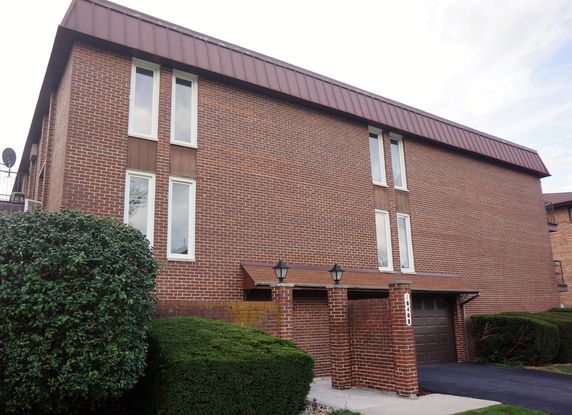 Front view of a multi-story brick building with tall windows and a garage entrance.