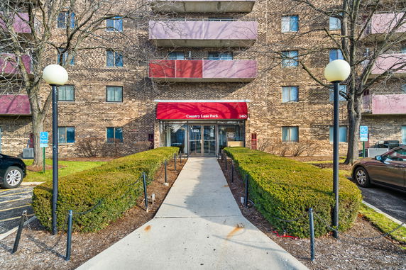 Front view of a multi-story brick building with balconies and a red awning entrance.