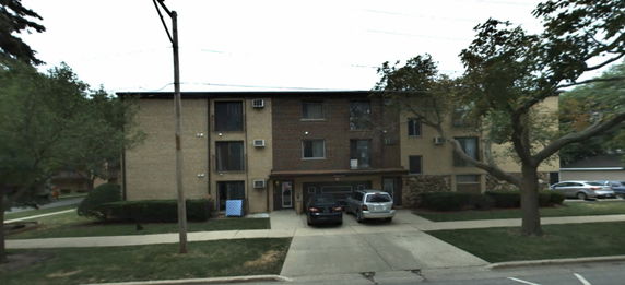 Front view of a multi-story apartment building with parking in front.