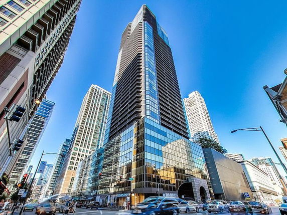 Front view of a tall skyscraper with reflective glass windows in an urban setting.