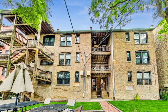 Rear view of a three-story brick apartment building with wooden balconies and staircases.