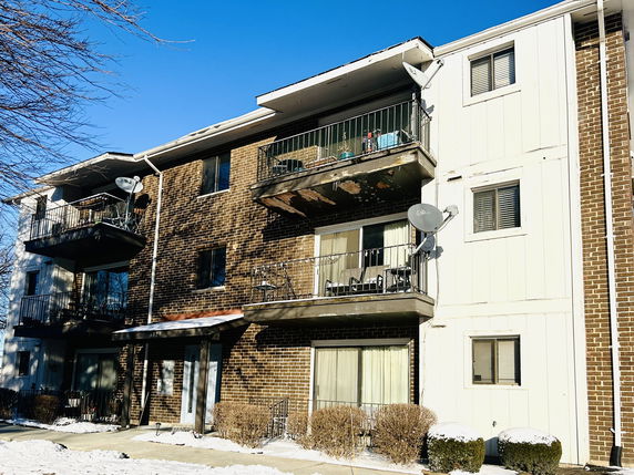 Front view of a multi-story brick apartment building with balconies.