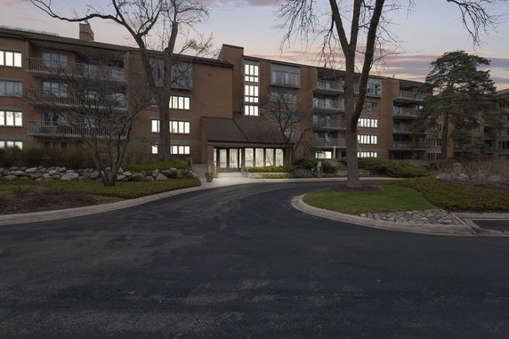 Front view of a multi-story brick building with balconies and a driveway.