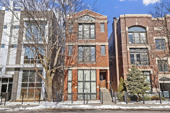 Front view of a multi-story brick building with large windows and a small front yard.
