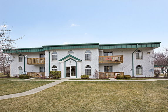 Front view of a two-story apartment building with a green roof and balconies.