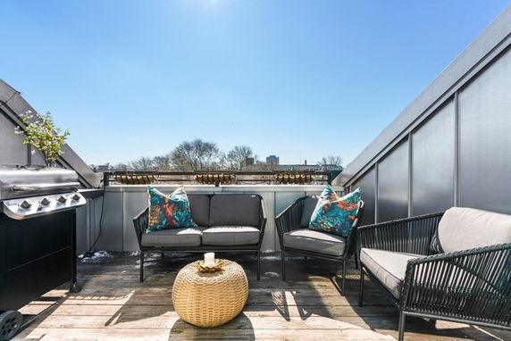 Rooftop area with outdoor seating and a grill.