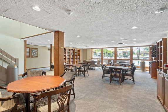 Open indoor area with multiple tables, chairs, and bookshelves.