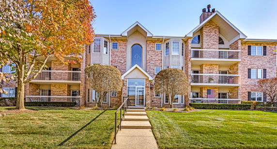Front view of a multi-story apartment building with balconies and a central entrance.