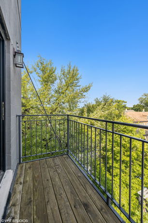 Balcony with a wooden floor and metal railing overlooking surrounding trees.