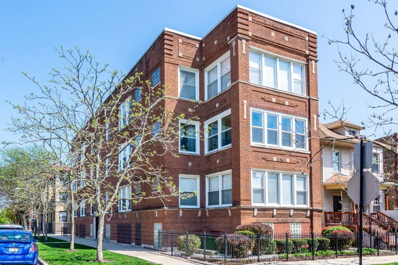 Front view of a multi-story brick building with large windows.