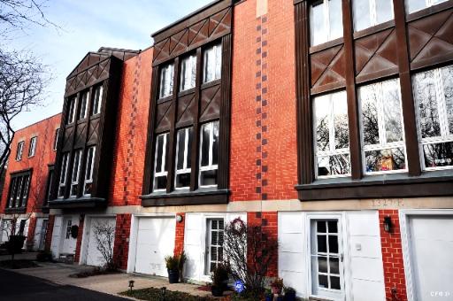 Front view of a row of modern multi-story townhouses with brick and dark trim facade.
