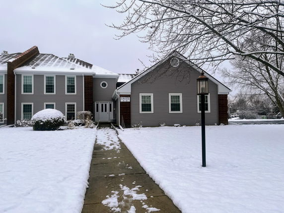 Front view of a two-story house with snow-covered surroundings.