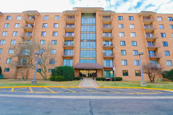 Front view of a multi-story brick apartment building with balconies.