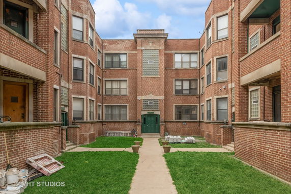 Front view of a brick residential building with multiple windows and a green door.