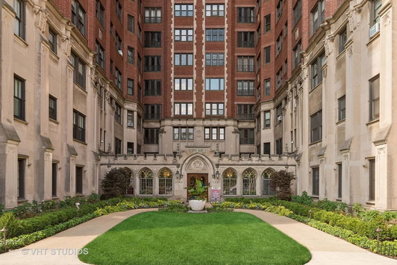 Front view of a multi-story brick and stone building with a landscaped courtyard.