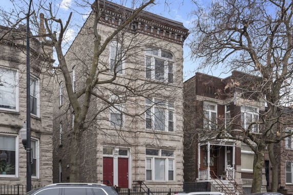 Front view of a multi-story residential building with brick facade and red doors.