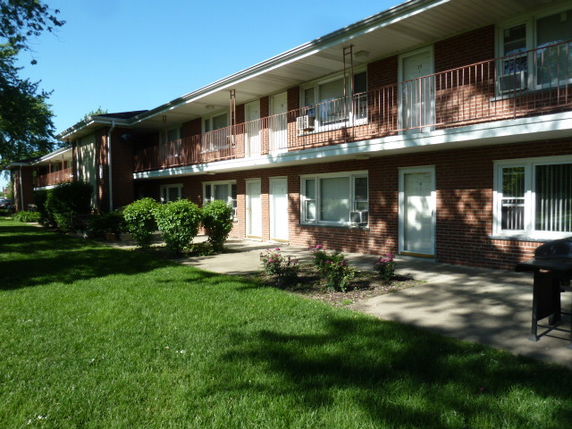 Front view of a two-story apartment building with brick exterior and balconies.