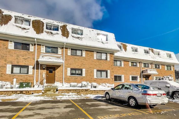 Front view of a multi-story brick building with snow on the roof.