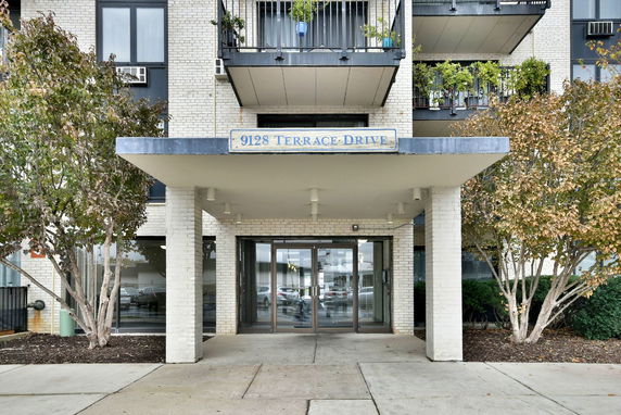 Front entrance of a multi-story building with a sign reading '9128 Terrace Drive.'